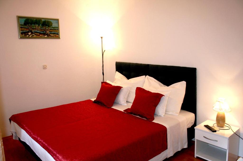 a bedroom with a red and white bed with red pillows at Rooms and Apartments Emily in Split