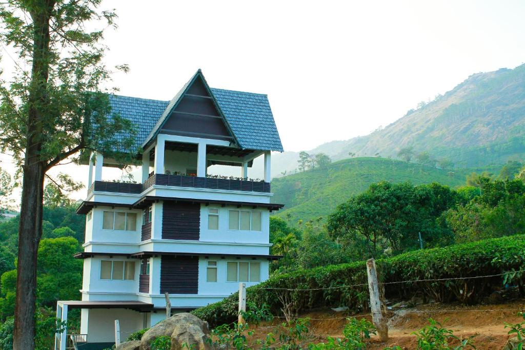 a blue house with a roof on a hill at Gruenberg Tea Plantation Haus in Munnar