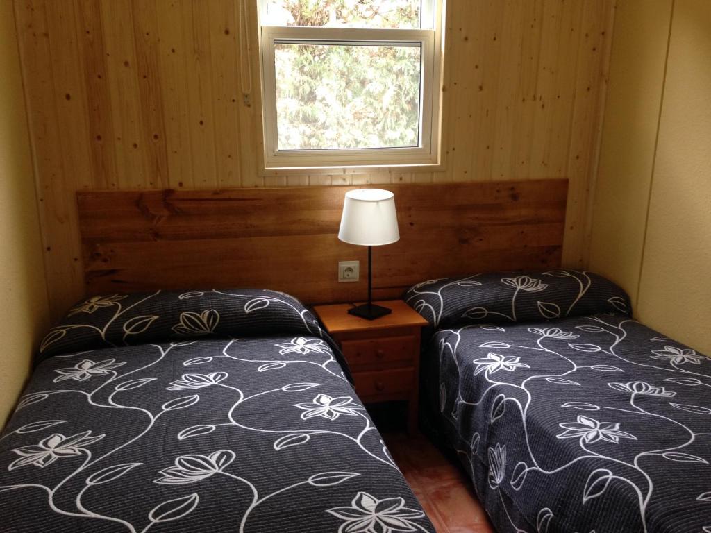 two beds in a small room with a window at Camping Cubillas in Cubillas de Santa Marta