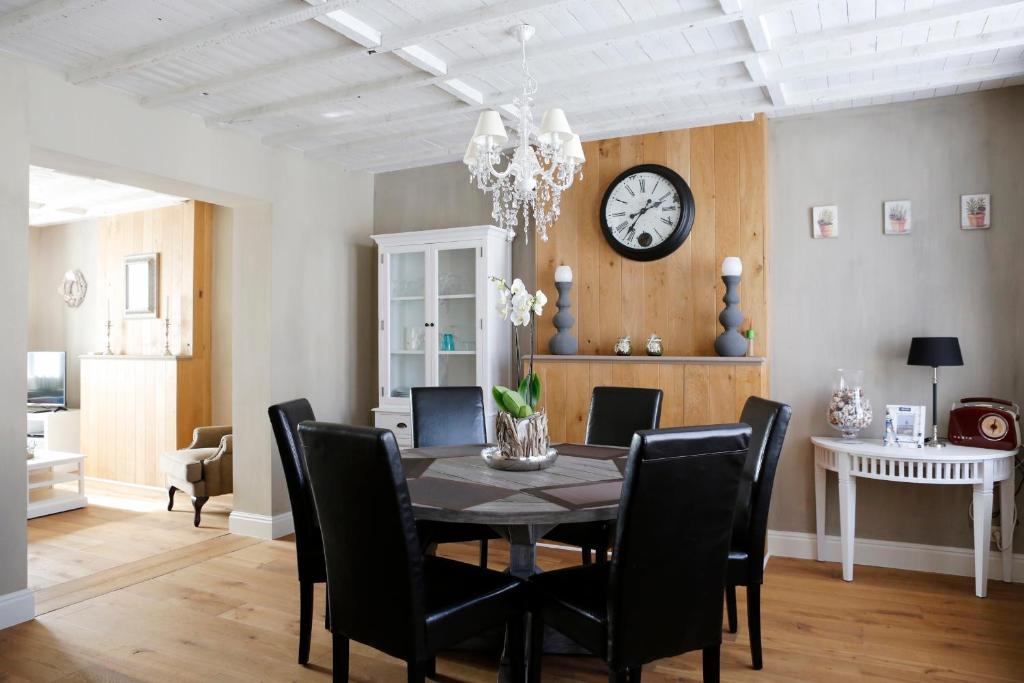 une salle à manger avec une table, des chaises et une horloge dans l'établissement Les Maisons de la Mer, à Ostende