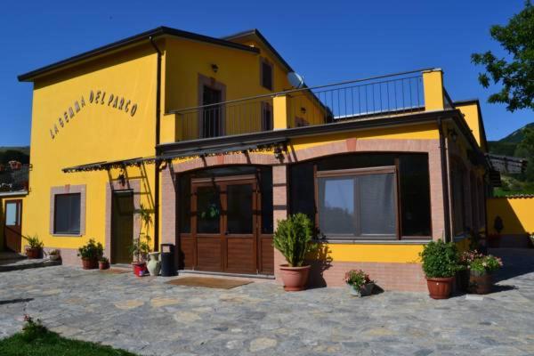 a yellow house with potted plants in front of it at Agriturismo La Gemma del Parco in Mormanno