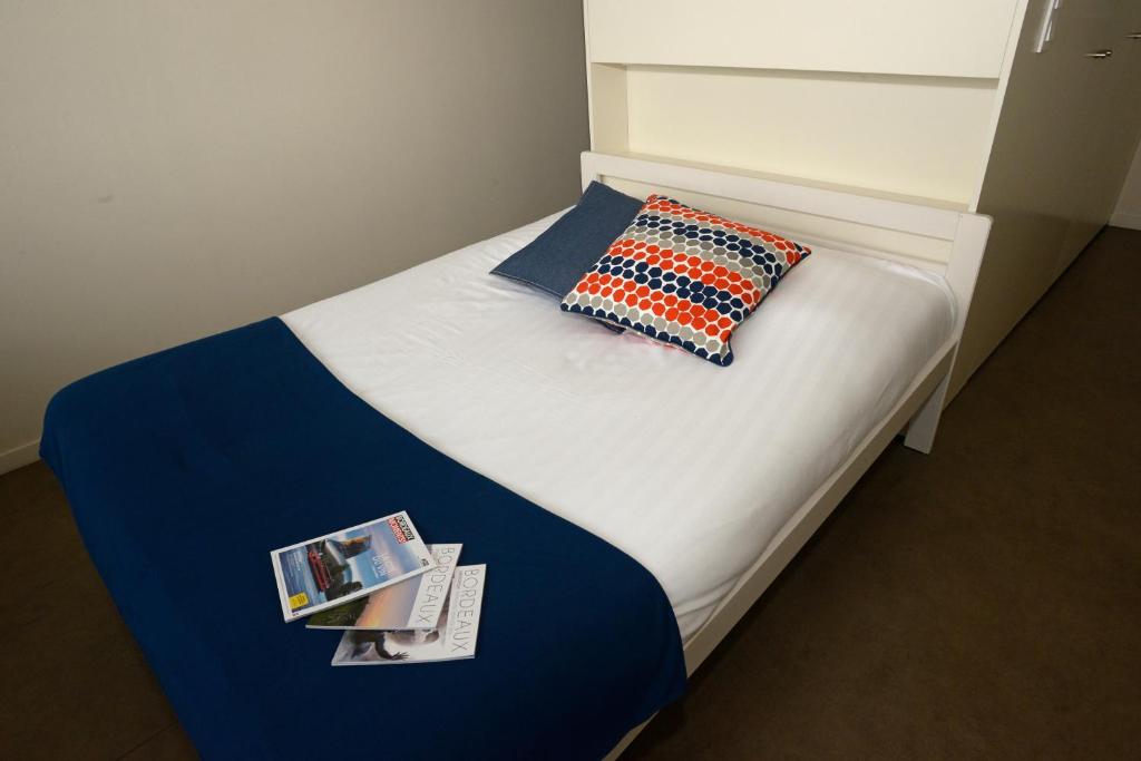 ロルモンにあるStudy Hôtel Bordeaux Lormontのベッド(枕付)、雑誌