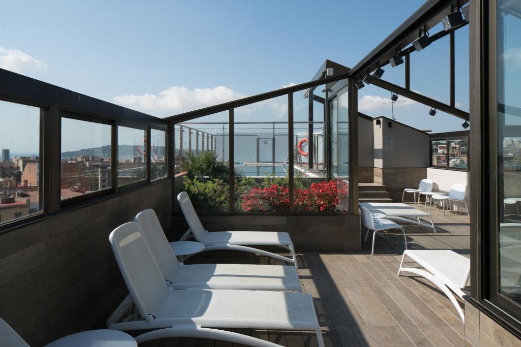 a balcony with white chairs and a view of the ocean at Catalonia Park Putxet in Barcelona