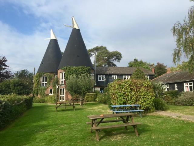 a building with two pointed roofs with benches in the grass at Playden Oasts Hotel in Rye