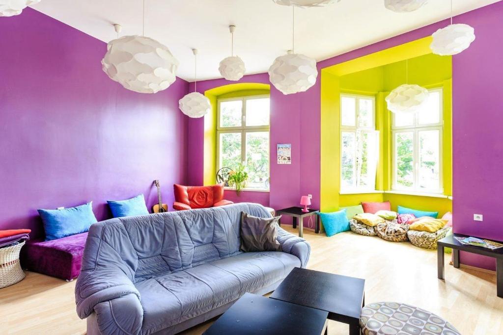 ein Wohnzimmer mit lilafarbenen Wänden und einem Sofa in der Unterkunft Grampa's Hostel in Breslau