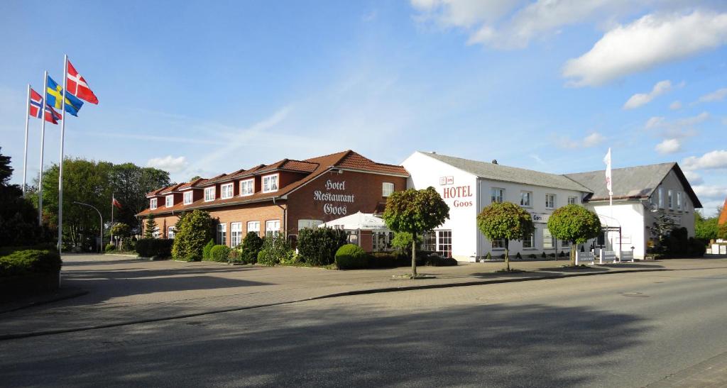 un bâtiment arborant des drapeaux sur le côté d'une rue dans l'établissement Hotel Goos, à Jübek