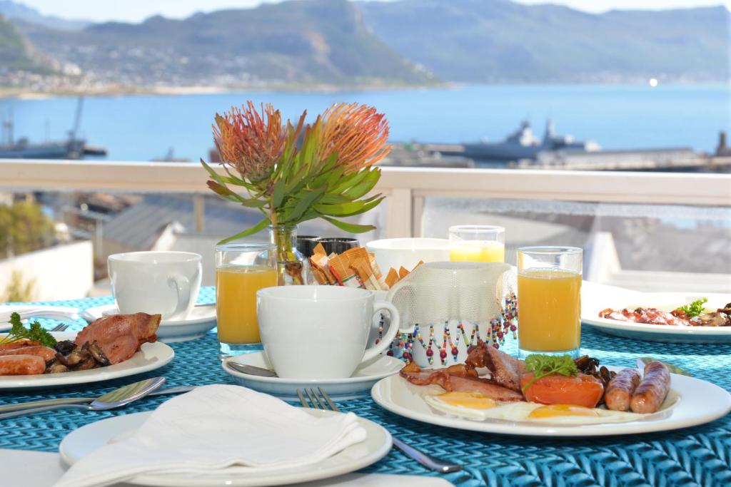 una mesa con platos de comida y zumo de naranja en The Grosvenor Guest House & Self Catering en Simonʼs Town