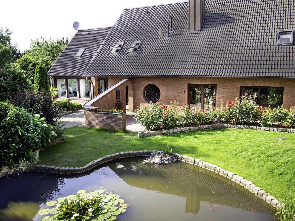 ein Haus mit einem Teich vor einem Haus in der Unterkunft Ferienwohnungen in Wremen in Wremen