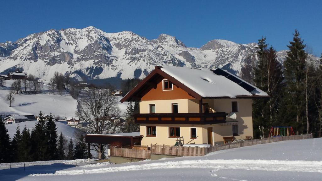 a house in the snow with mountains in the background at Ferienhaus Almfrieden in Schladming