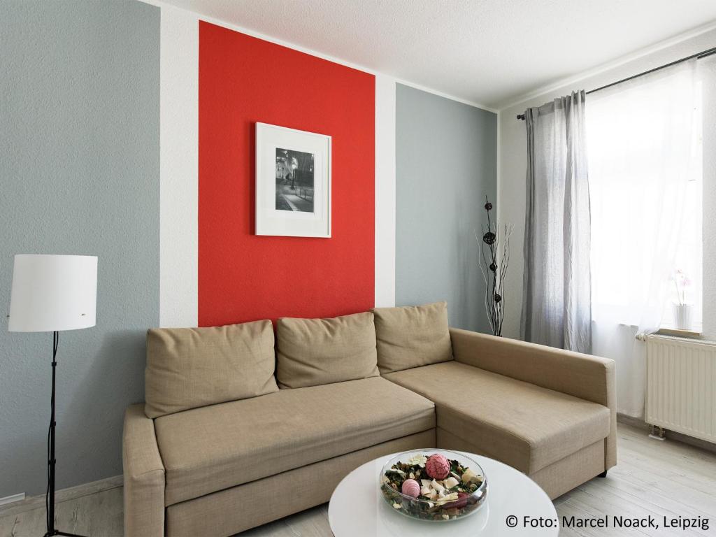 ein Wohnzimmer mit einem Sofa und einer roten Wand in der Unterkunft City Park Apartments - #1-8 - Stilvolle Apartments zentrumsnah in Leipzig