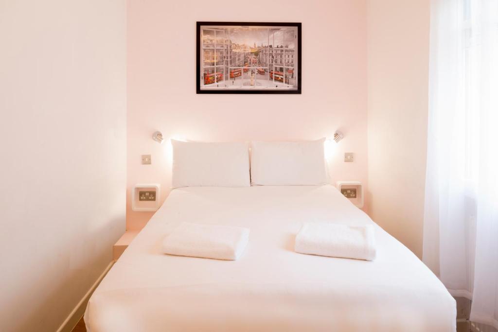 a bedroom with a white bed with two white pillows at The California - London Kings Cross in London