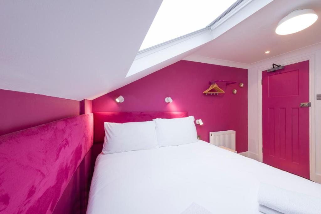 a purple bedroom with a white bed and a red door at The California - London Kings Cross in London