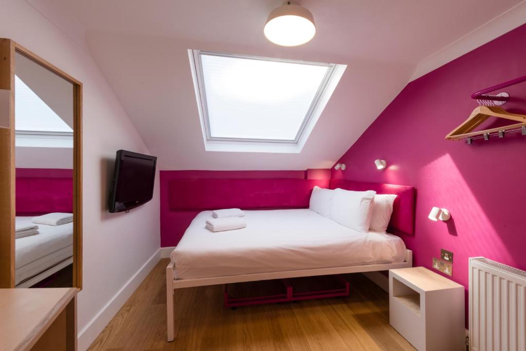 a bedroom with pink walls and a bed with a mirror at The California - London Kings Cross in London