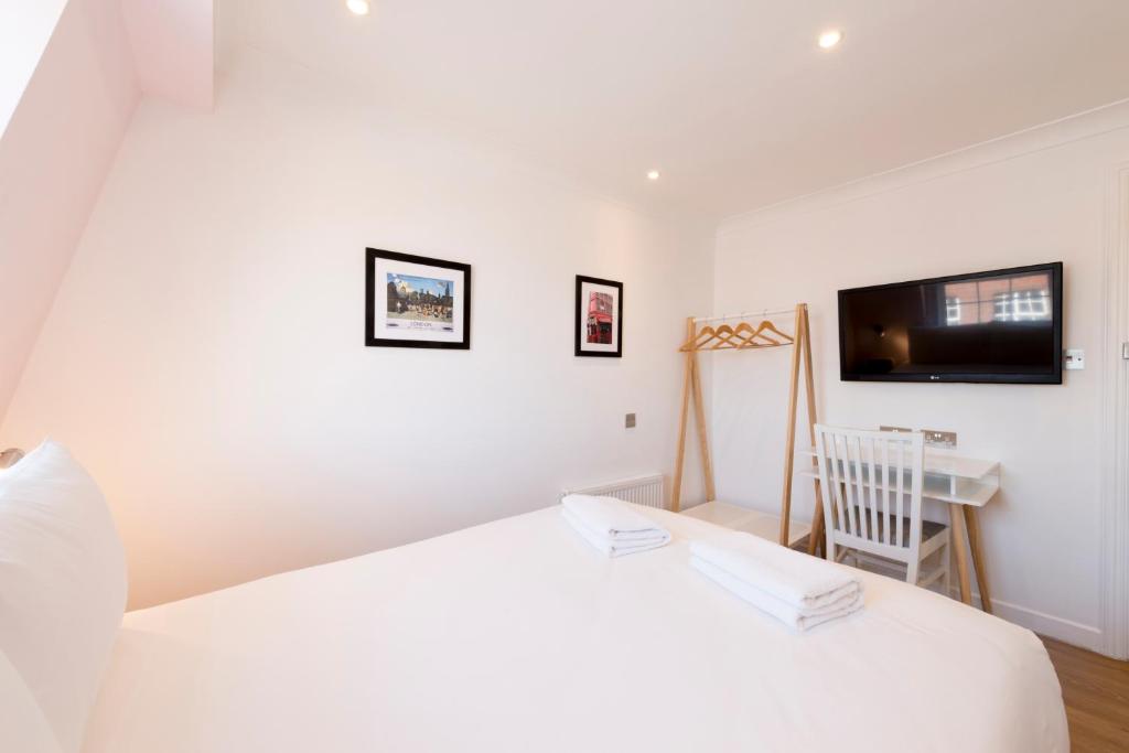 a white bedroom with a bed and a television at The California - London Kings Cross in London