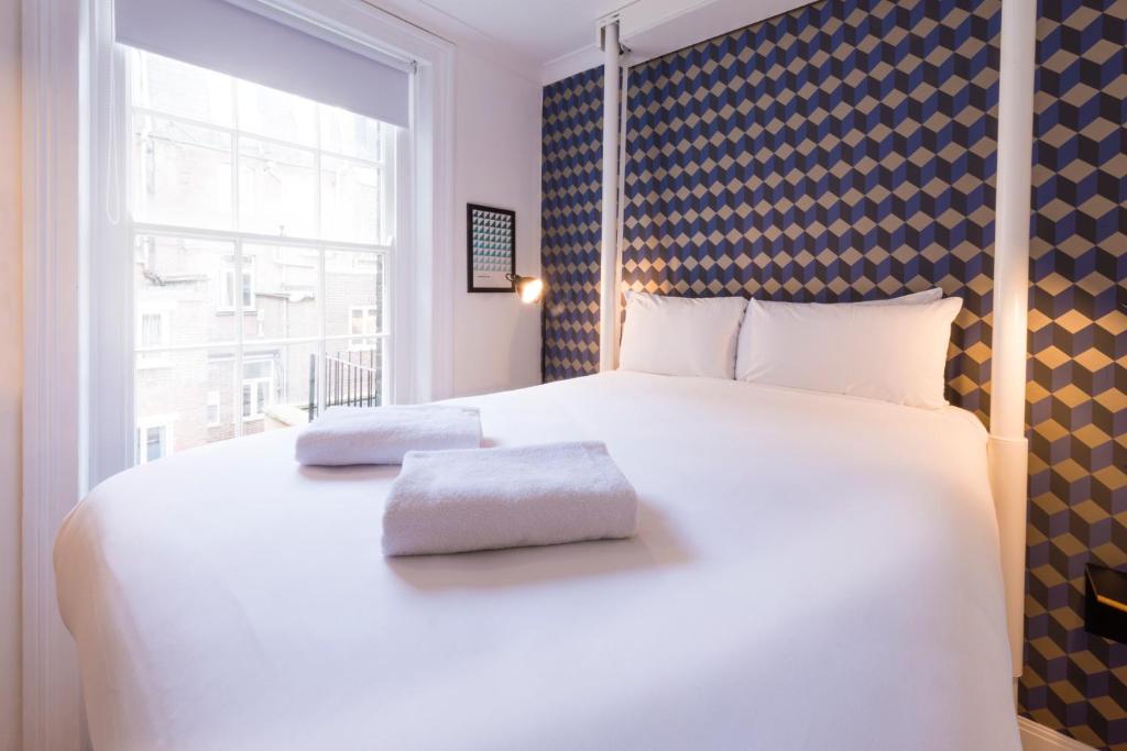 a bedroom with a large white bed with a window at The California - London Kings Cross in London