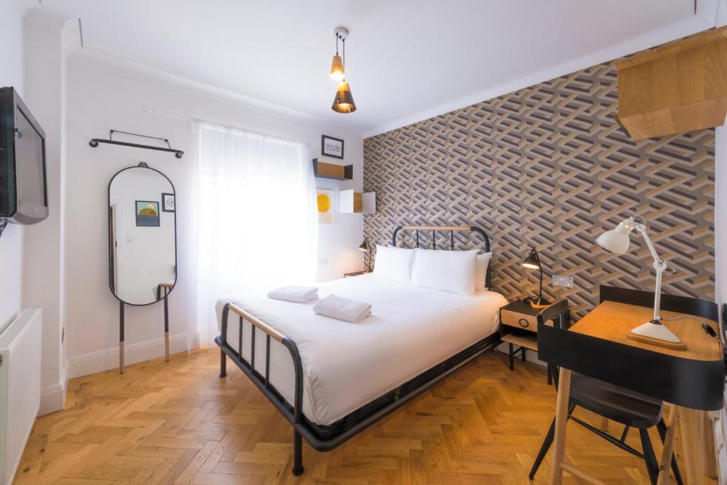 a bedroom with a bed and a desk and a tv at The California - London Kings Cross in London