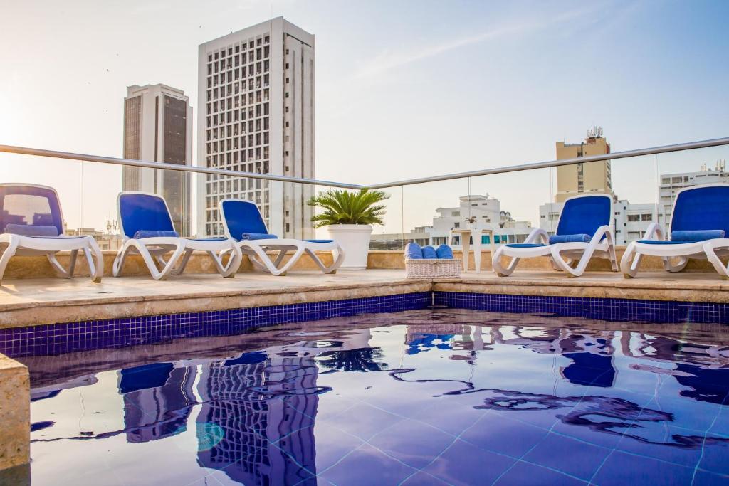 einen Pool auf dem Dach mit Stühlen und Stadtblick in der Unterkunft Hotel Boutique La Artilleria in Cartagena de Indias