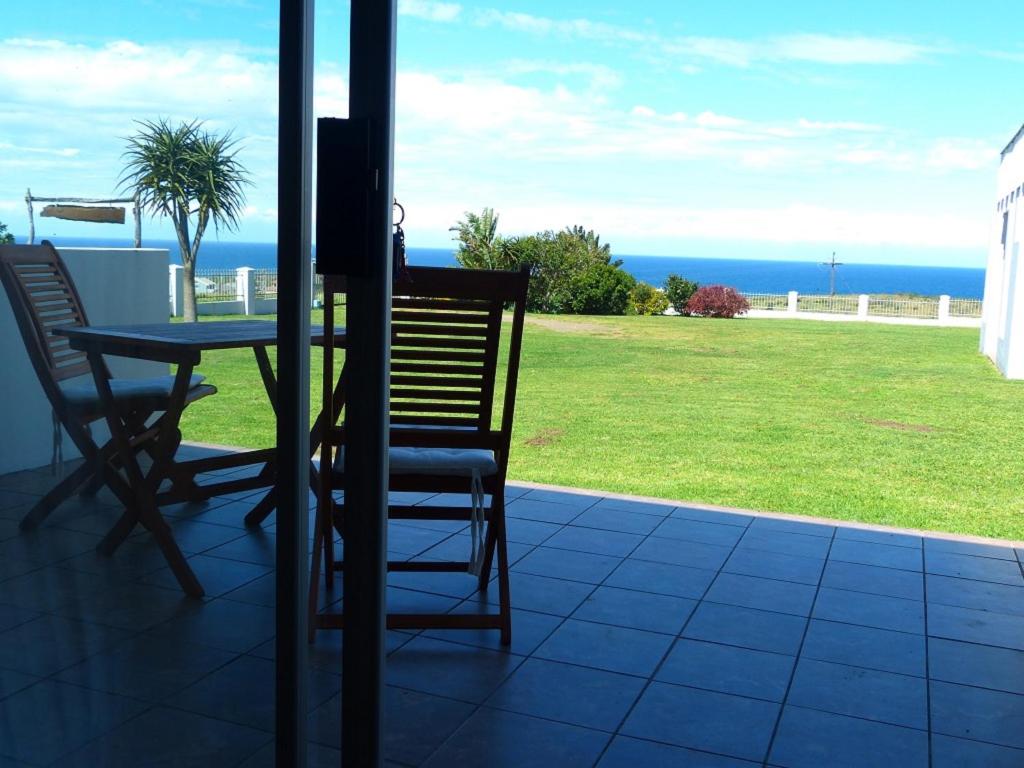 une terrasse avec une table et des chaises et l'océan dans l'établissement Tayside Guest House, à Kiddʼs Beach