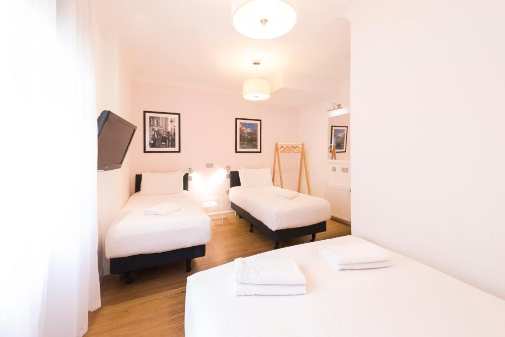 a room with two beds in a room with white furniture at The California - London Kings Cross in London