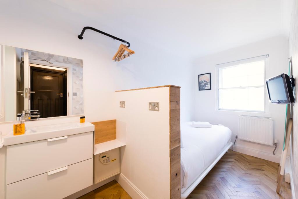 a bedroom with a bed and a sink and a mirror at The California - London Kings Cross in London