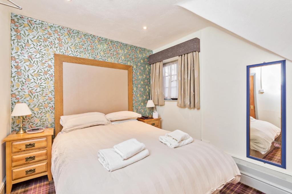 een slaapkamer met een groot bed en 2 handdoeken bij Duke of Wellington in Bourton on the Water