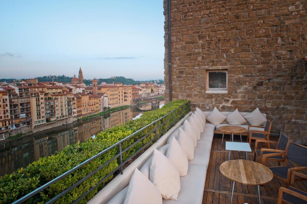 uma varanda com almofadas e mesas brancas num edifício de tijolos em Hotel Continentale - Lungarno Collection em Florença