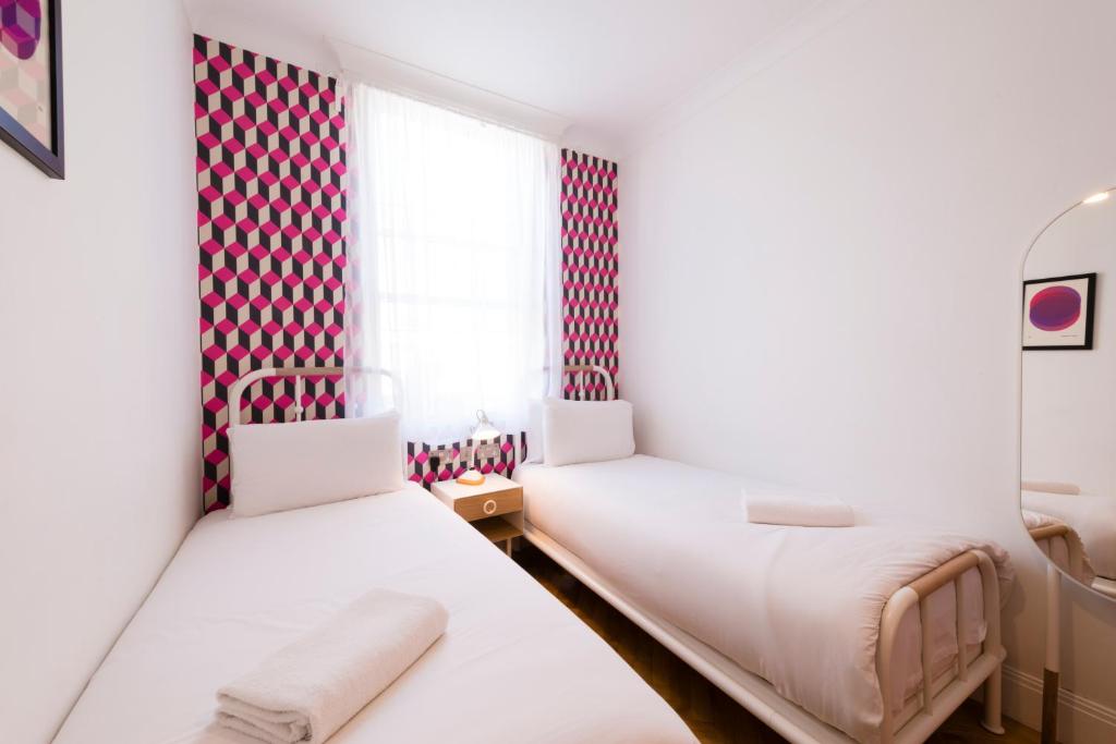 two beds in a room with red and white wallpaper at The California - London Kings Cross in London