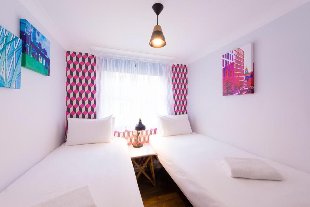 two beds in a room with red and white curtains at The California - London Kings Cross in London