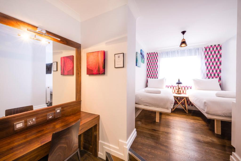 a room with two beds and a mirror at The California - London Kings Cross in London
