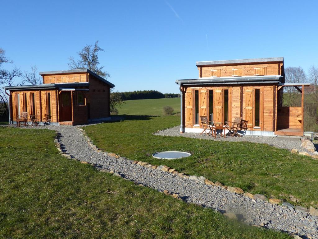 eine große Holzhütte auf einem Feld neben einem Grasfeld in der Unterkunft Chalets am National Park Eifel in Schleiden