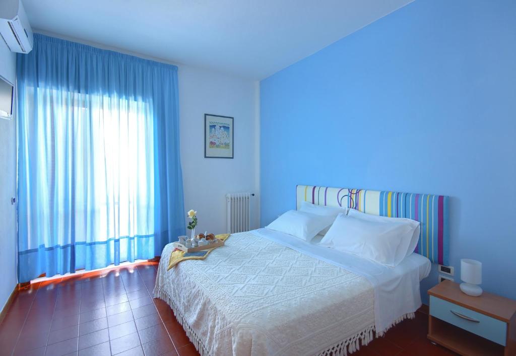 a blue bedroom with a bed and a large window at Iris Hotel in Ischia