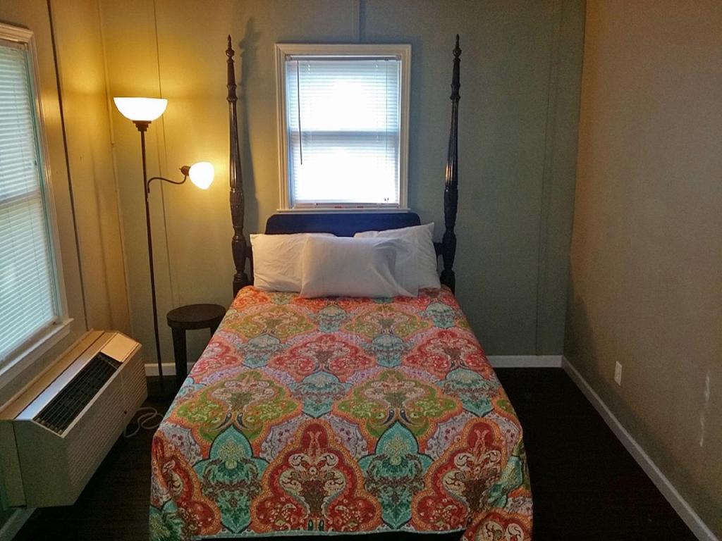 1 dormitorio con 1 cama con edredón y ventana en Carolina Landing Camping Resort Two-Bedroom Cabin 1, en Fair Play