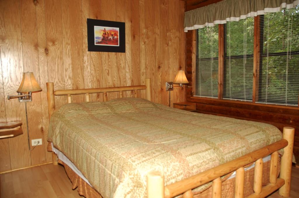 a bedroom with a bed in a room with wooden walls at Carolina Landing Camping Resort Cabin 10 in Fair Play