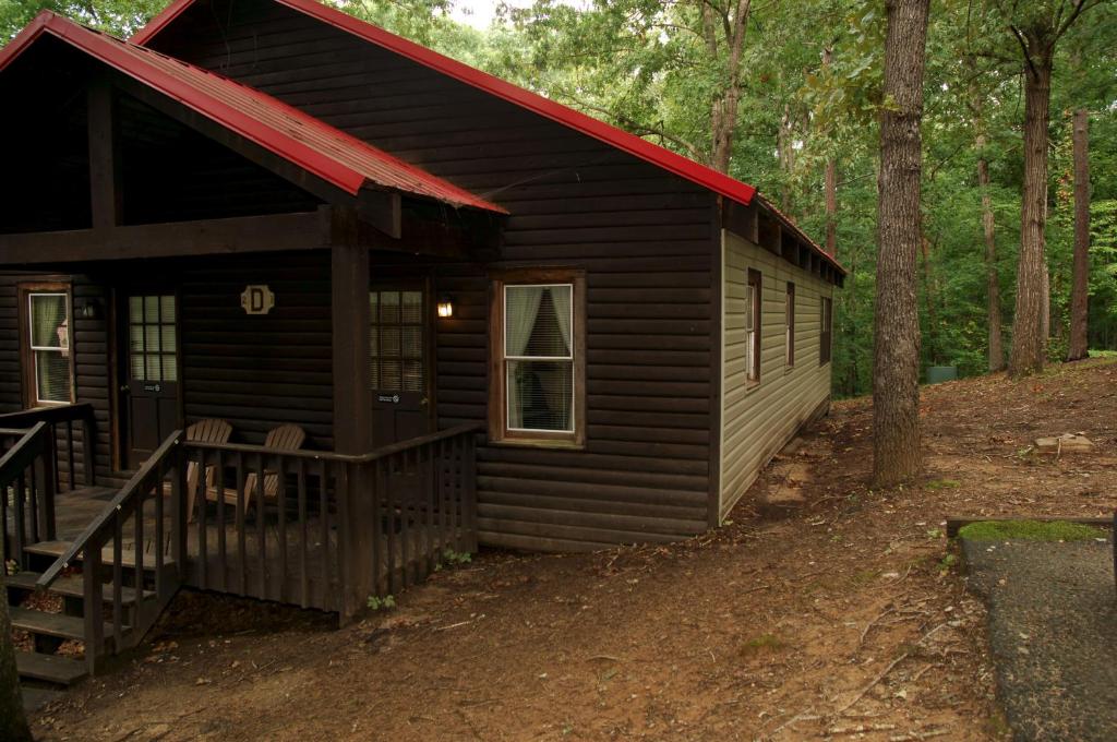 una cabaña en el bosque con techo rojo en Carolina Landing Camping Resort Deluxe Cabin 6, en Fair Play