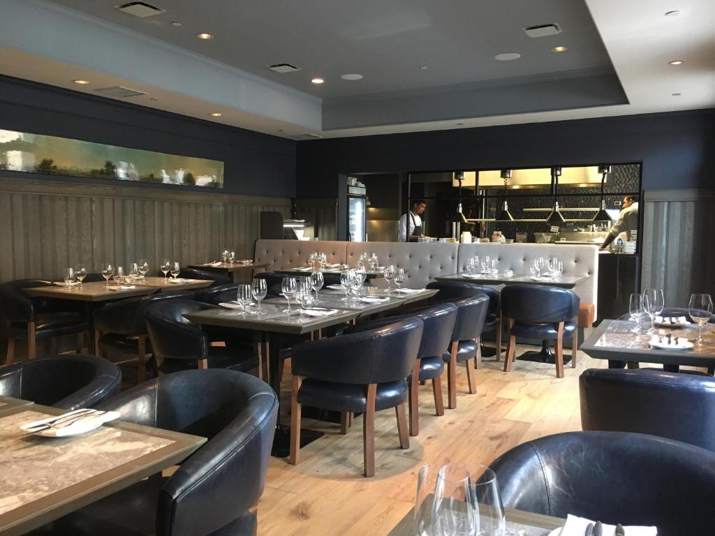a restaurant with tables and chairs and a chef in the background at Hotel Arts Kensington in Calgary