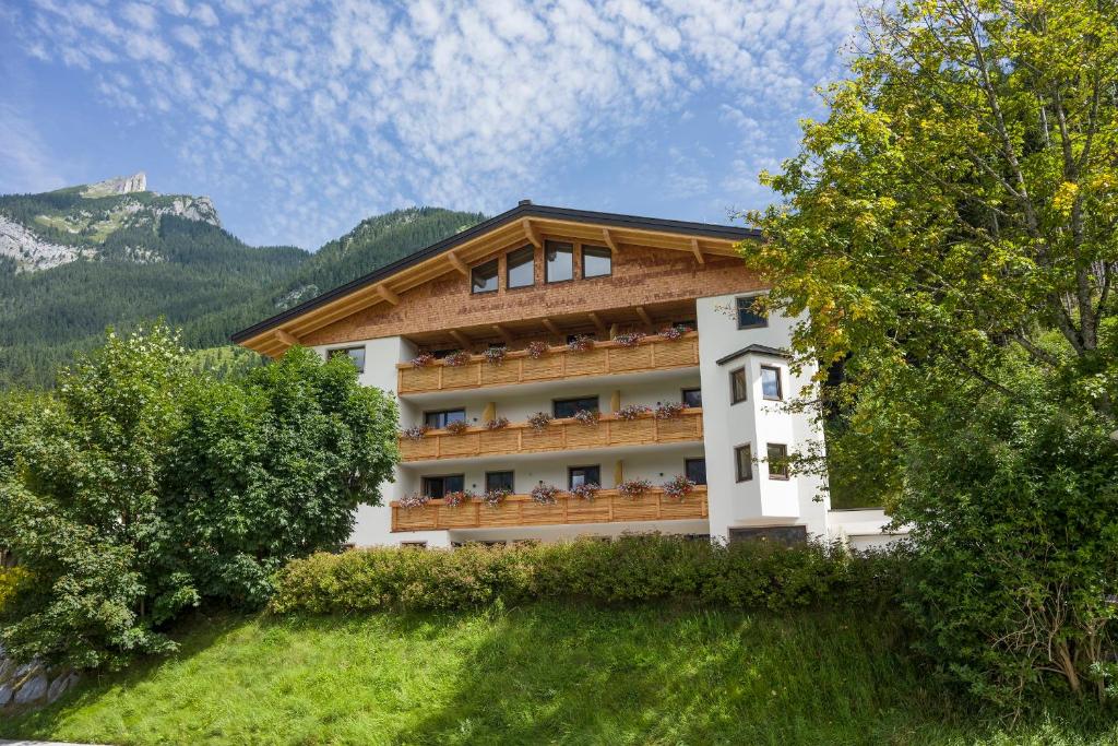 a building with a balcony with trees and mountains at Appartements Rofan in Maurach