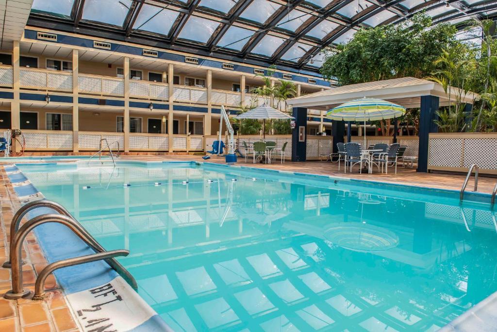a large swimming pool with chairs and a building at Ramada by Wyndham Indianapolis Speedway in Indianapolis