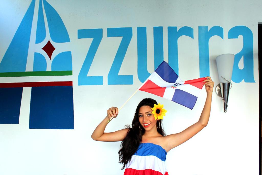 a woman holding a kite in front of a sign at Aparta Hotel Azzurra in Boca Chica