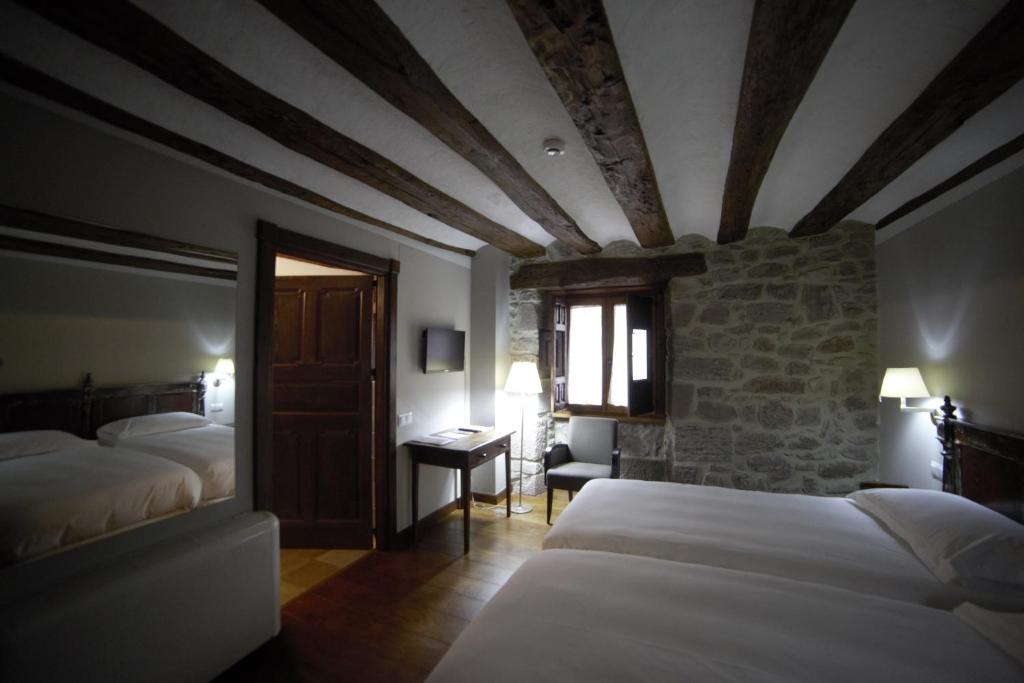 Hotel Rural LATORRIÉN DE ANE في Mues: غرفة نوم بسريرين وجدار حجري
