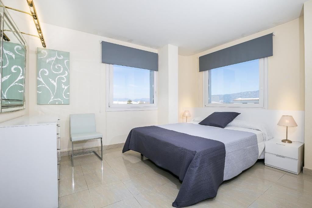 a bedroom with a large bed and two windows at Maurici Park in Empuriabrava