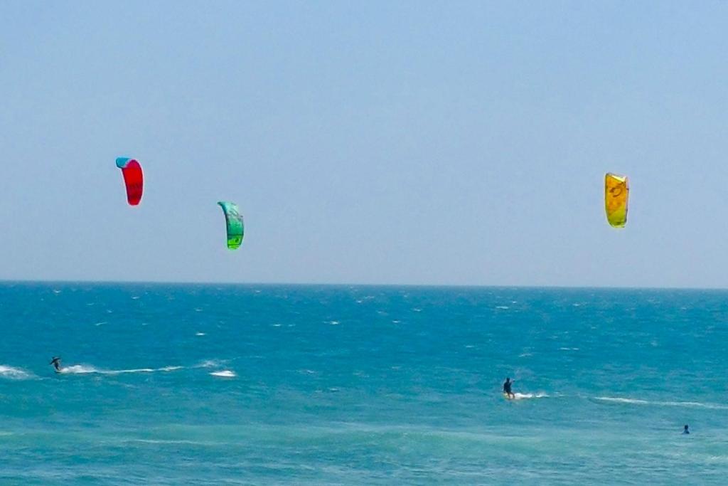 tres personas en el océano volando cometas en el océano en Apartamento Barra Pé na Areia, en Río de Janeiro