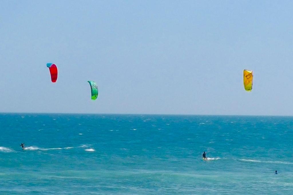Hotel Apartamento Barra Pé na Areia, three people in the ocean flying kites in the ocean at Apartamento Barra Pé na Areia in Rio de Janeiro