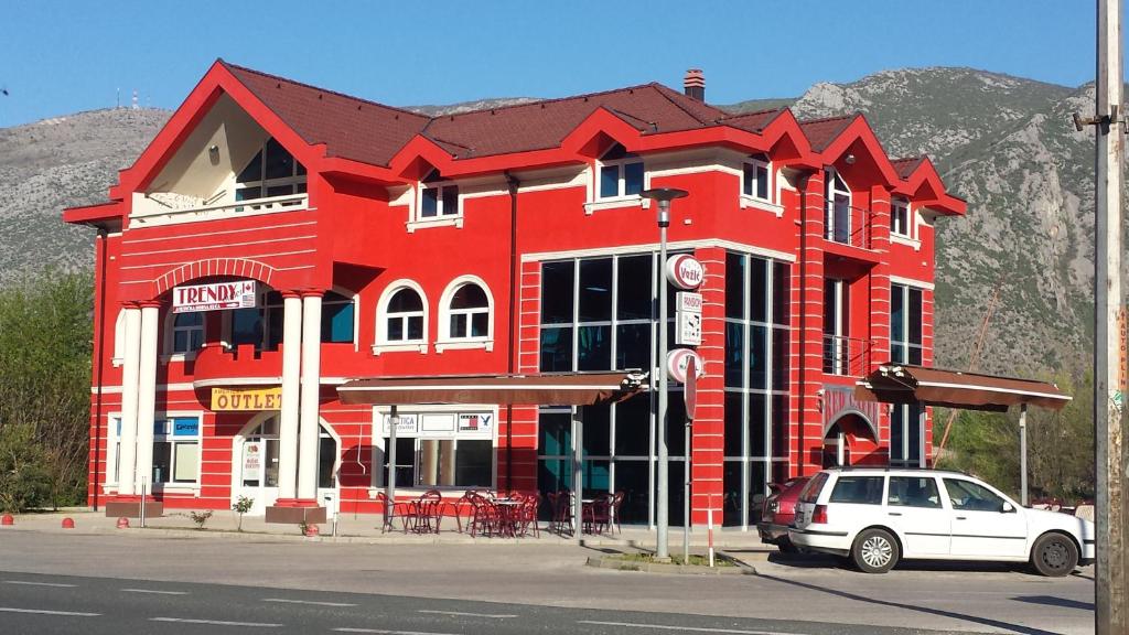 un edificio rojo con un coche blanco aparcado delante de él en Villa Vežić, en Mostar