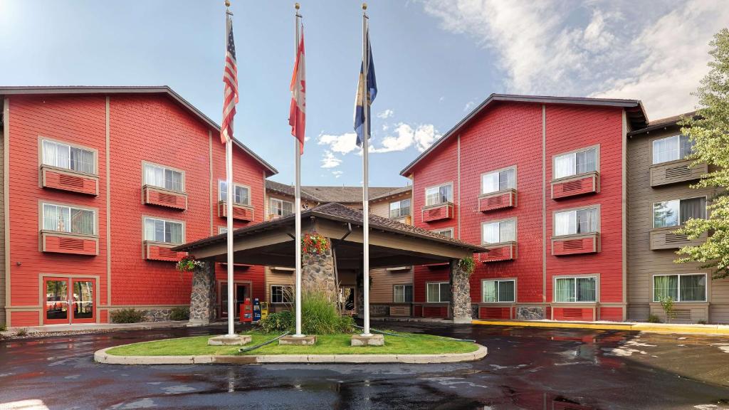 a red hotel with two flags in a parking lot at Best Western Rocky Mountain Lodge in Whitefish