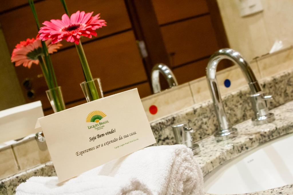 a sign sitting on a bathroom sink with flowers at Leques Brasil Hotel Escola in Sao Paulo