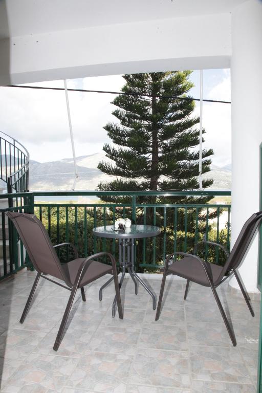 a table and chairs on a balcony with a pine tree at Villa Elena in Lixouri