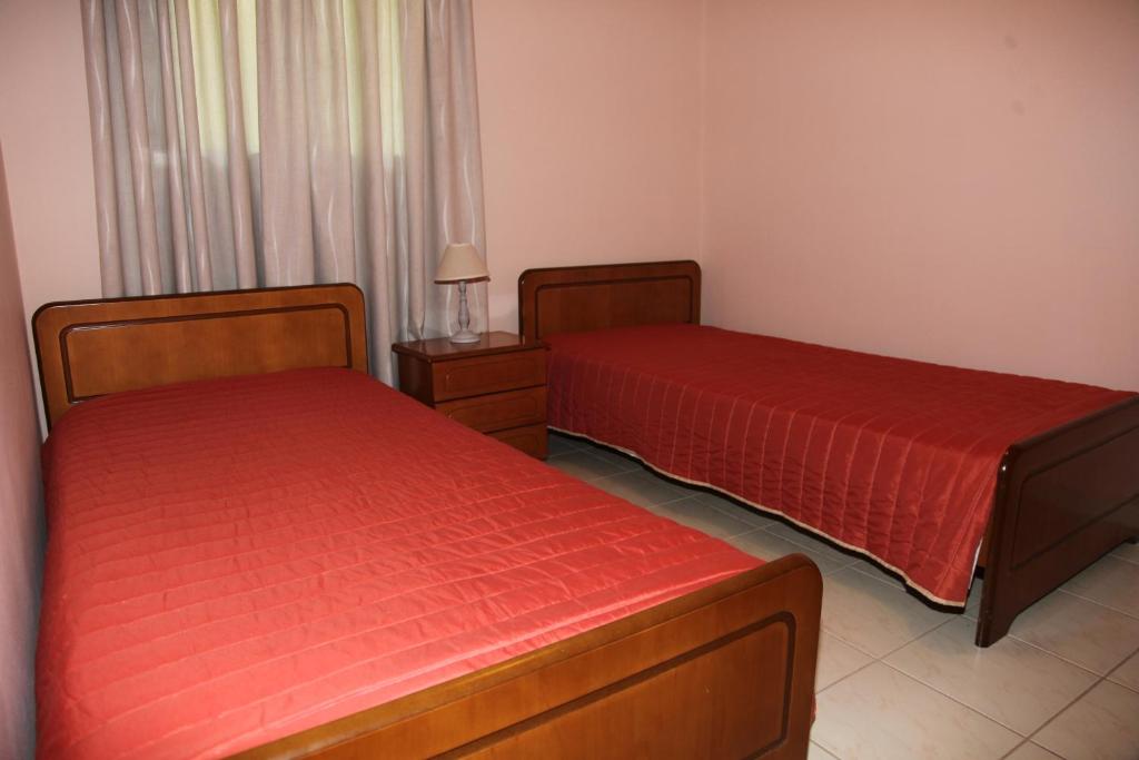 two beds with red sheets in a room at Villa Elena in Lixouri