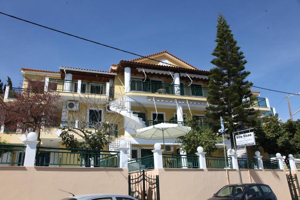 un gran edificio amarillo con una sombrilla delante de él en Villa Elena en Lixouri