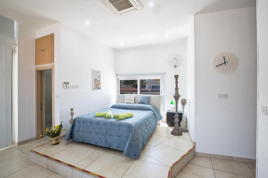 um quarto com uma cama azul num quarto branco em Pallini Court em Protaras