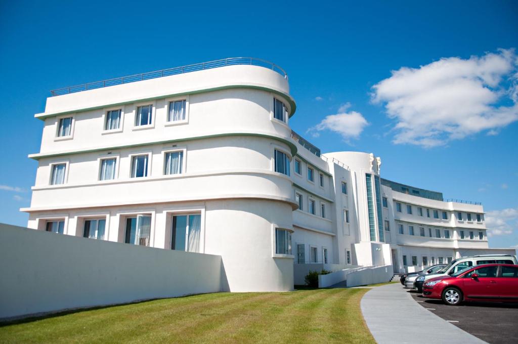 un bâtiment blanc avec des voitures garées devant lui dans l'établissement Midland Hotel, à Morecambe